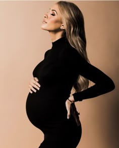 a pregnant woman posing for the camera in a black dress with her hands on her hips