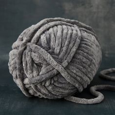 a ball of gray yarn sitting on top of a black table next to a pair of scissors