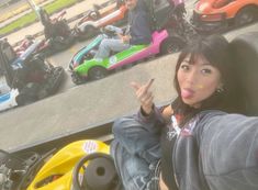 a woman sitting on the back of a motorcycle next to other people in go karts