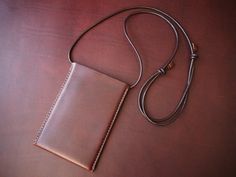 a brown leather case sitting on top of a wooden table next to a lanyard