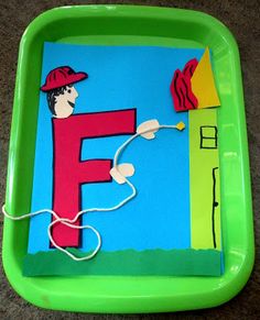 a green tray that has some paper cutouts on it with the letter f in red