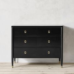 a black dresser with gold handles against a white wall