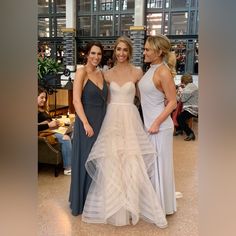 three beautiful women standing next to each other in formal wear at a wedding reception, posing for the camera