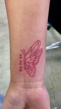 a small tattoo on the wrist of a woman with a pink butterfly in her left arm