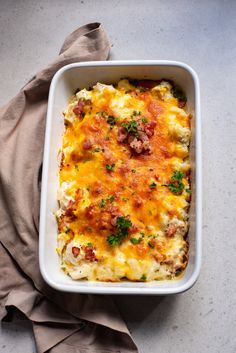 a casserole dish with meat and cheese in it on a cloth next to a napkin