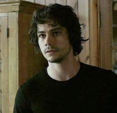 a man with curly hair and black shirt looking at the camera