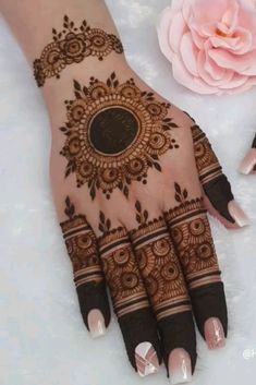 henna tattoo on the palm of a woman's hand next to a pink flower