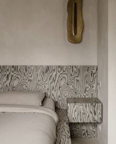 a bed sitting next to a wall with a clock on it's sideboard