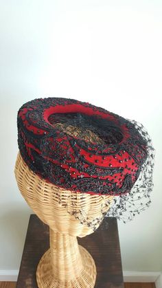 This stunning vintage hat features a striking red silk-velvet base that perches elegantly atop the head; dramatic, faceted black beading; a black net veil and center; and winding ribbon-like corde detailing. Era: 1940s Label: Macy's New York Rise: about 2.75 inches tall 7.5 inches long over top, front to back Victorian Fitted Hats For Evening, Fitted Victorian Hat For Evening, Vintage Cloche Headpieces For Evening, Red Evening Hat Headpiece, Elegant Bead Caps Headpieces For Evening, Elegant Evening Headpieces With Bead Caps, Net Veil, Formal Cocktail Party, Hourglass Dress