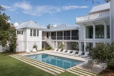 a house with a swimming pool in front of it and several lawn chairs around the pool