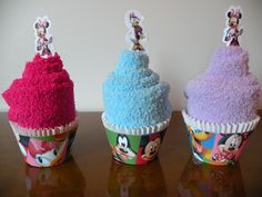 three mickey mouse cupcakes with frosting on them sitting on a wooden table