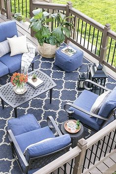 an outdoor patio with blue furniture and potted plants on the balcony railing, surrounded by greenery