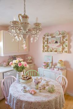 there is a table with tea cups on it in the room and flowers are sitting on the table