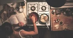 a woman is reading a book while cooking in the kitchen