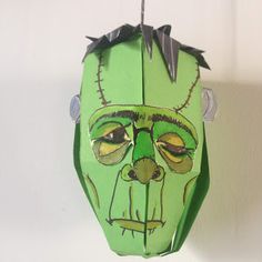 a green paper mask hanging from a wall