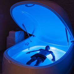 a man is swimming in an illuminated bathtub