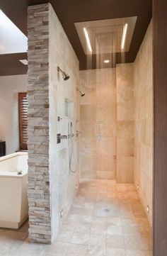 a walk in shower sitting next to a white tub