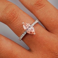 a woman's hand with a pink diamond ring on top of her finger,