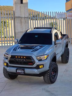 a silver truck parked in front of a white fence