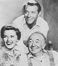 an old black and white photo of two men and a woman smiling at the camera