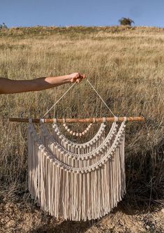 a person is holding up a small macrame in the middle of a field