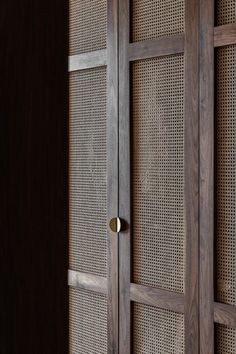 a wooden cabinet with metal handles and wicker panels on the front, in a dark room