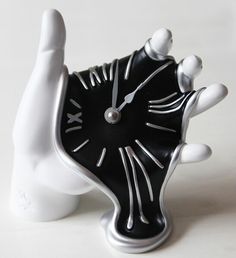 a black and white clock sitting on top of a table next to a plastic hand