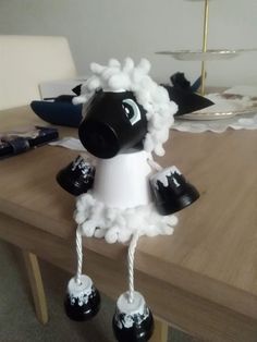 a black and white sheep sitting on top of a wooden table