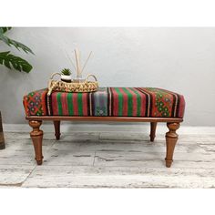 a wooden bench with a multicolored blanket on it's back and legs