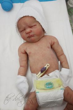 a newborn baby wearing a white hat and diaper