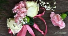 pink and white flowers are tied together on a wooden surface with ribbon around them, along with baby's breath