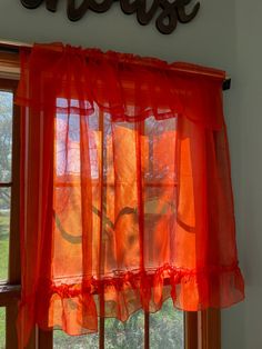 an orange curtain hanging in front of a window with the word love spelled on it