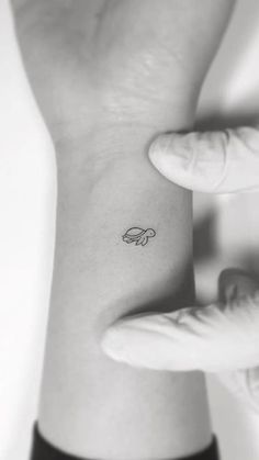 a woman's wrist tattoo with a small butterfly on it, in black and white