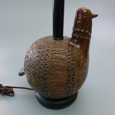 a ceramic bird lamp sitting on top of a black base with a cord plugged into it