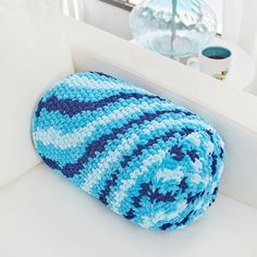 a crocheted blue and white blanket sitting on top of a couch next to a window