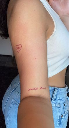 a woman with a heart tattoo on her left arm and right arm behind her back