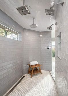 a walk in shower sitting next to a white tiled wall and wooden stool on the floor