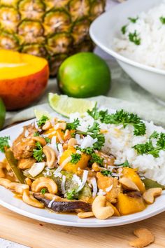 a white plate topped with rice and veggies next to pineapples on a table