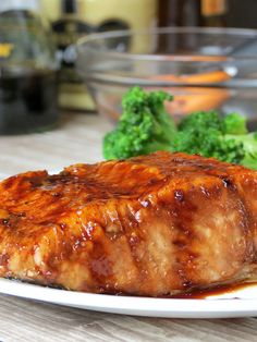 a plate with meat and broccoli on it sitting next to a glass bowl