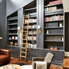 a living room filled with lots of bookshelves next to a couch and chair