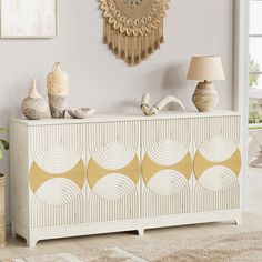 a white and yellow dresser with gold accents in a living room next to a lamp