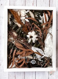 a white box filled with lots of different types of leaves and flowers on top of a wooden floor