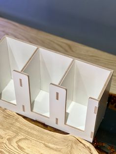 three empty white boxes sitting on top of a wooden table next to a piece of wood