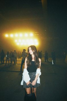 a woman standing in front of a stage at night with her hands on her hips