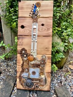 an art piece made out of scrap wood and metal parts sitting on top of gravel