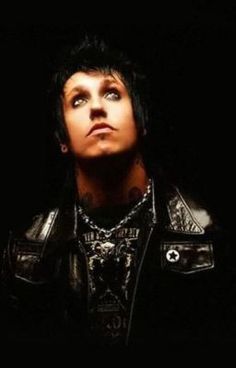 a man with black hair and piercings wearing a leather jacket looking up into the sky