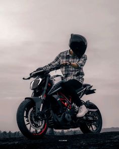 a man riding on the back of a motorcycle down a dirt road in front of a cloudy sky