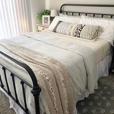 a bed with white linens and pillows in a bedroom next to a window curtain