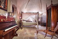 a bedroom with a canopy bed, piano and chair in the room next to it