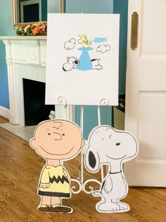 a charlie brown and snoopy standing next to each other in front of a sign